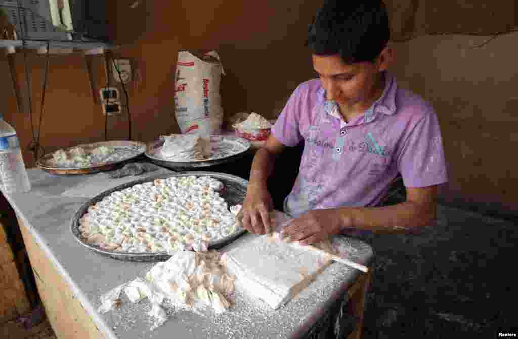 A boy makes pastry at a shop in Darkush town, Idlib province, May 26, 2013.